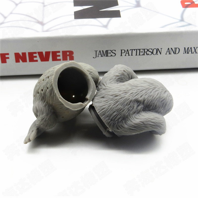 Sloth tea infuser separated into two pieces, showing the hollow tea compartment beside a book
