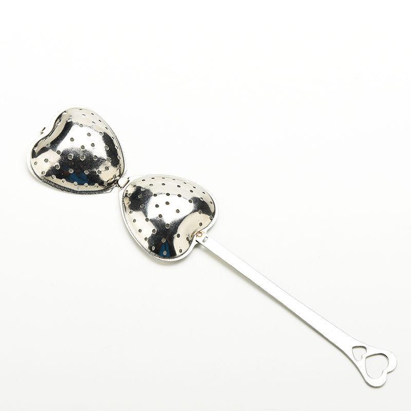 Open heart-shaped stainless steel tea infuser with perforated halves and a long handle ending in heart shapes